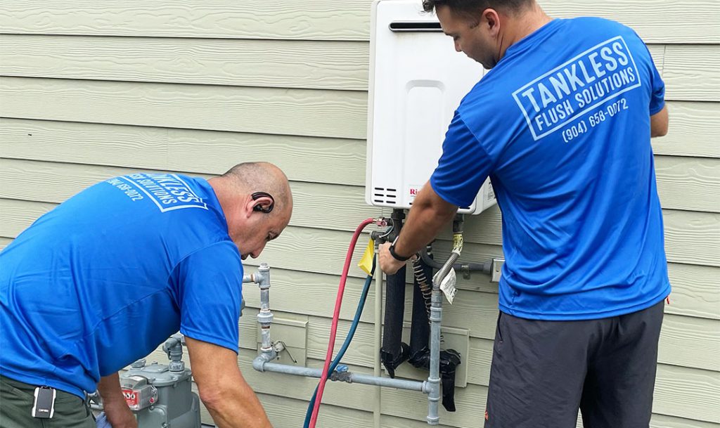 Two men servicing a tankless water heater.